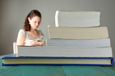 Young woman (30 -35) read a book behind a pile of books. Women education concept. real people copy spaceの写真素材