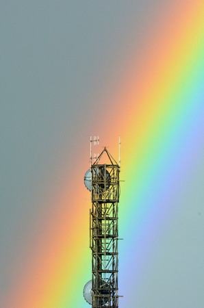 Colorful rainbow hits a communication tower with satellite dish and aerials. Telecommunication concept. copy spaceの写真素材