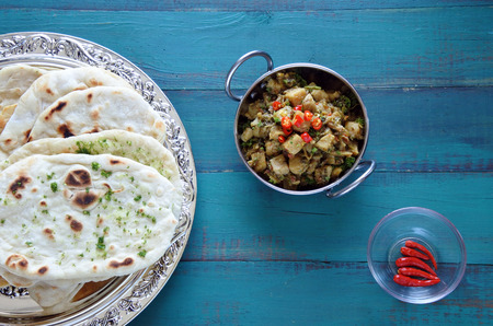 Flat lay view of Indian Alu Methi cuisine served with Naan flatbread and fresh chilli.Food...