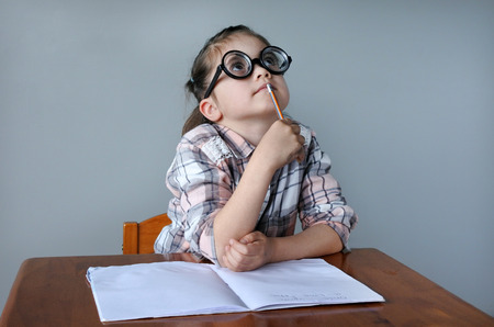 Nerdy child  (girl age 6 -7) search for inspiration. Children childhood education conceptの写真素材