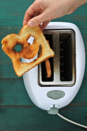 Flat lay view of hand holds one slices of toast bread against a  toaster. Happiness concept. copy spaceの写真素材