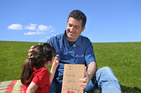 Young girl gives her father flower and a card reading:I LOVE YOU DADDY. Children,  Childhood, fatherhood and parenthood concept.の写真素材