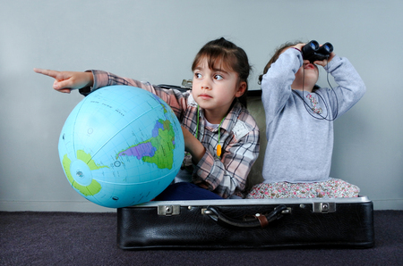 Two children (girls age 02 and 06) playing at home a kids traveler game in a travel suitcase. Children, travel, holiday, vacation and trip concept.の写真素材