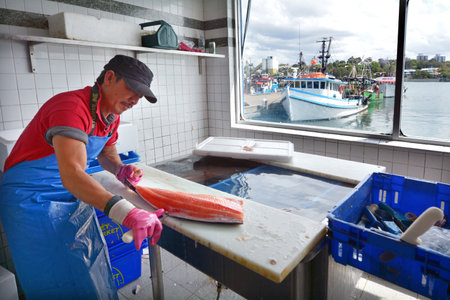 Sydney, Australia - OCT 20 2016: Fisherman cleans a Salmon fish in Sydney Fish Market, a Large marketplace  and a major tourist attraction featuring shops for seafood, deli items and restaurants.のeditorial素材