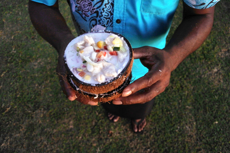 Indigenous Fijian Man serves Fijian Food, Kokoda (Raw Fish Salad). Kokoda is Fiji's version of ceviche, enriched with coconut milk to balance out all the acid.Real people, copy spaceの写真素材
