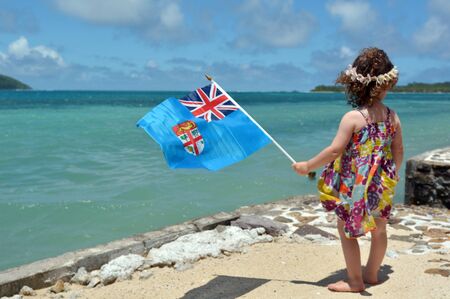 Little girl on family travel holiday vacation in Fiji waving the National flag of the Republic of Fiji. Real People copy spaceの写真素材