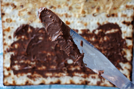 Spread knife full of chocolate above Matzo with chocolate during the Passover Jewish holiday. Food background and texture. copy spaceの写真素材
