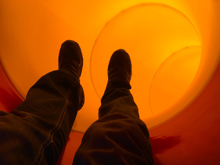 Man legs sliding down through a pipe slide.Dream concept.copy spaceの写真素材