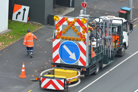 Auckland, New Zealand - May 19, 2017: A road construction worker walks next to a road construction...