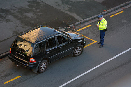 AUCKLAND, NEW ZEALAND - JUNE 08 2017: Traffic Police officer writing a traffic citation to a car driver on the side of the road in Auckland city central, New Zealand. Traffic Police Monitor traffic to ensure motorists observe traffic regulations and exhibのeditorial素材
