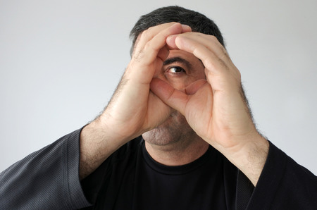 Man pretends to peek through a hole with his hands (age 40). Real people. Privacy concepts and ideas. Copy spaceの写真素材