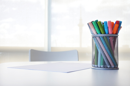 Colourful pens and blank white paper on a table with chair. Creativity concept. Copy spaceの写真素材