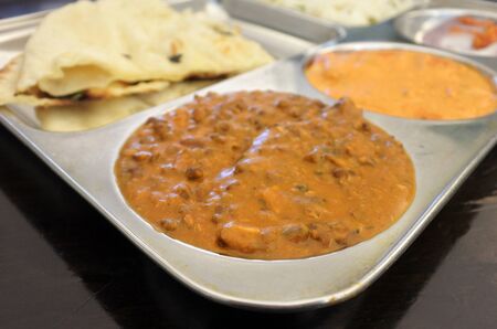 Indian food vegetarian dish of lentil dal, rice, butter tofu curry and naan bread served on a tray...