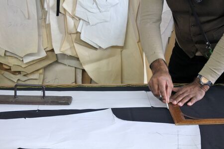 Hands of professional tailor chalking measurements on table in traditional tailors shop studio. Creativity concept. Real people. Copy spaceの写真素材