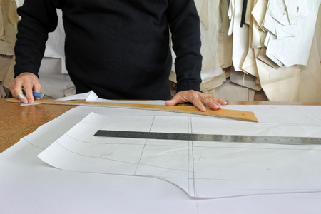 Hands of professional tailor chalking measurements on table in traditional tailors shop studio. Creativity concept. Real people. Copy spaceの写真素材