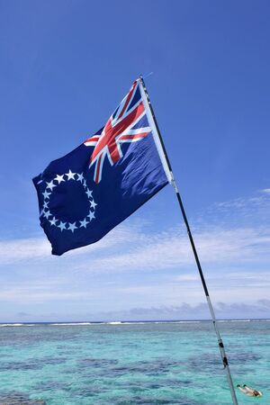 Cook Islands Ensign against Rarotonga coral reef. Pacific Island travel holiday vacation concept. Copy spaceの写真素材