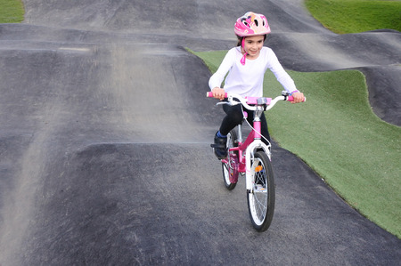 Young girl (age 08) rides a bicycle on obstacle trek in a public park.の写真素材