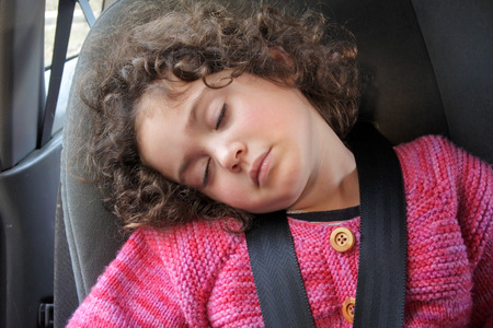 Small girl (age 03) sleeping in a car seat during a road trip.の写真素材