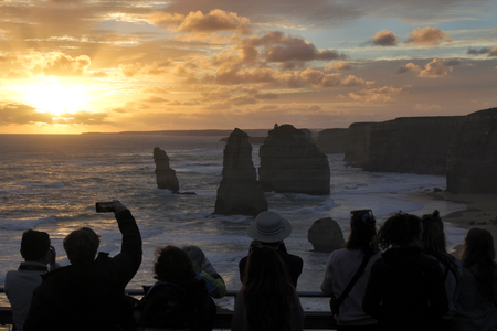 Silhouette of unrecognizable tourists at Port Campbell National Park, looking at the Twelve Apostles during sunset along the Great Ocean Road in Victoria, Australia.の写真素材