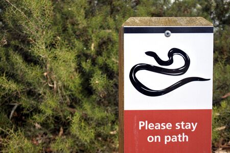 A snake icon with please stay on path text on outdoor sign in Australian park.