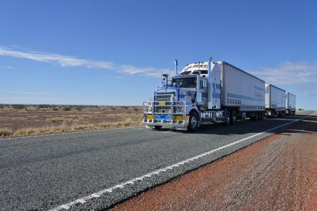Coober Pedy, South Australia - May 20 2019: Three-trailer road train driving in central Australia Outback.Road train is a trucking vehicle used in remote areas of Australia,USA and Europe to move freight efficiently.のeditorial素材