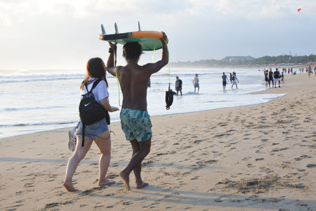 Bali, Indonesia - July 23 2019:Japanese woman and Balinese male gigolo walking on Kuta beach.Bali's beaches are renowned for their male gigolos and Japanese Women travel to Bali for sex with local beach boys.のeditorial素材