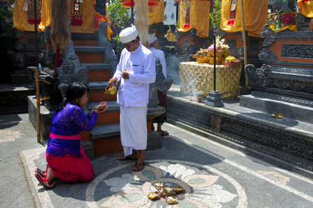 Ubud, Bali, Indonesia - July 24 2019:Hindu priest blessing Balinese family celebrating Galungan Kuningan holidays in a family temple in Ubud Bali, Indonesia.のeditorial素材