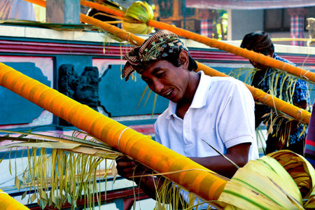 Bali, Indonesia - July 28 2019:Balinese men preparing Traditional Bali Penjor bamboo pole with decoration in a temples in Bali Indonesia on Galungan Kuningan holidaysのeditorial素材
