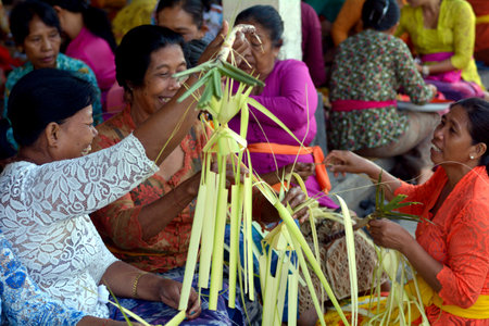 Bali, Indonesia - July 28 2019:Balinese women preparing Traditional Hindu offering decoration in a temples in Bali Indonesia on Galungan Kuningan holidays.のeditorial素材