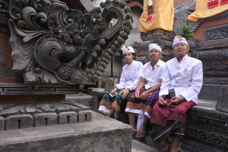 Three generation of Balinese men celebrating Galungan Kuningan holidays in a family temple in Ubud Bali, Indonesia.の写真素材