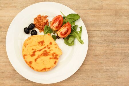 Flat lay view of Traditional Moroccan bread served on a white plate with fresh vegetables, tuna and...