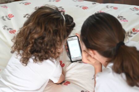 Two young girls (age 10 and 6) reading a text massage on a mobile phone. Real people. Copy spaceの写真素材