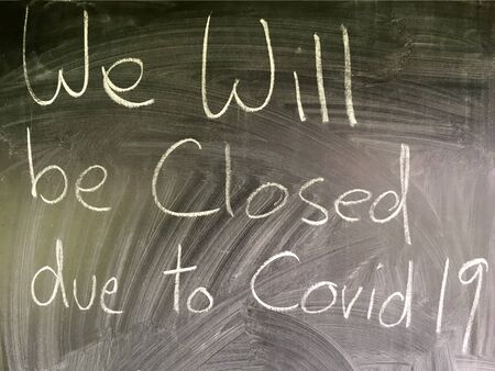 We will be closed due to COVID-19 message written in handwriting on a chalkboardの写真素材