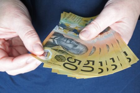 POV (Point of view) of young adult Australian woman counting cash of Australian dollar banknotes close up.の写真素材