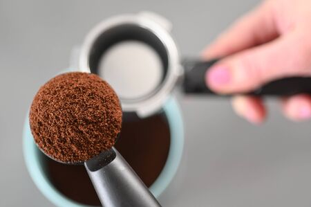 POV (Point of view) of woman filling coffee into portafilter on kitchen counter.の写真素材