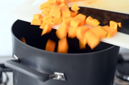 Motion blur of chopped pumpkin slices falling into a large cooking pot.の写真素材