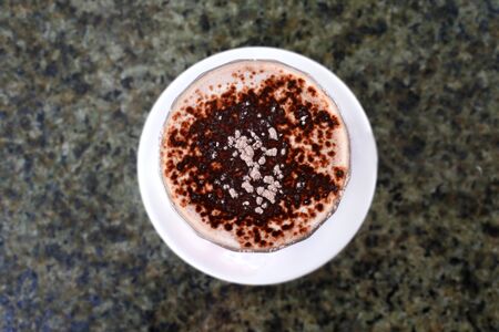 Flat lay view of hot chocolate drink served in a tall glass cup on marble table. in cafe restaurant.の写真素材