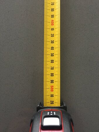 Close up of tape measure on green surface. Measuring tape is a flexible ruler used to measure size...