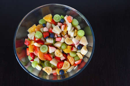Flat lay view of fruit salad bowl isolated on black background.