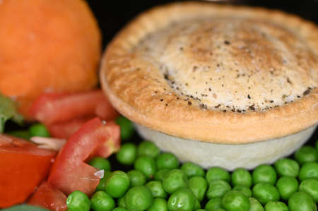 Hot meat pie served with  fresh salad and cooked peas and sweet potato.