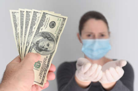 Point of view of a person handing out Federal Reserve Bank Notes to unemployed woman due to COVID-19 pandemic crisis.の写真素材
