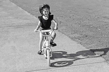 Happy young girl (age 06) riding a bike on a path in the park. Concept photo of child, health care, education, freedom  and happiness. Real people. Copy spaceの写真素材