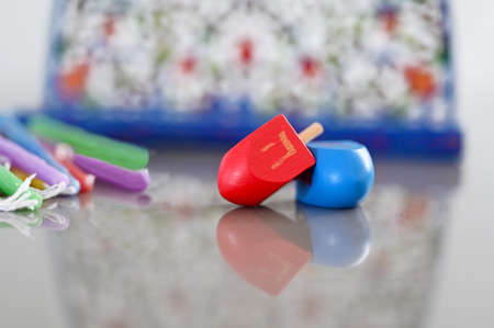 Dreidels (spinning top) and colorful candles beside a Menorah candelabra on Hanukkah Jewish holiday.の写真素材