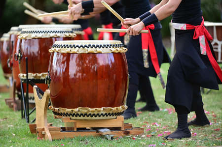 Group of Taiko drummers drumming on Japanese Drums together.の写真素材