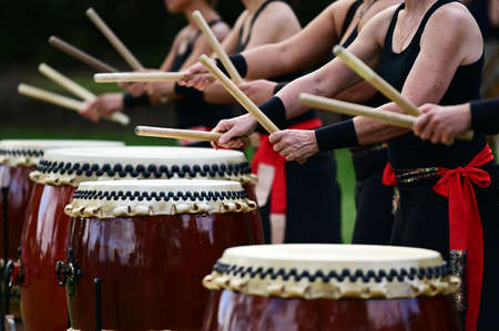 Group of Taiko drummers drumming on Japanese Drums together.の写真素材