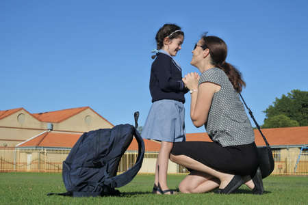Mother (age 30-40) talking to daughter (age 6-7) before going to schoolの写真素材