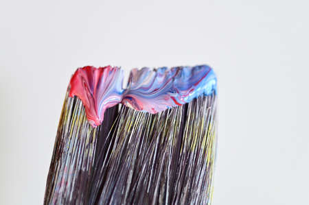 Close up of colorful paint on a paint brush isolated on a white wall abstract background and textureの写真素材