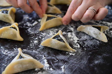 Low angle view of Jewish woman preparing one Hamantash cookie for Purim Jewish holiday.