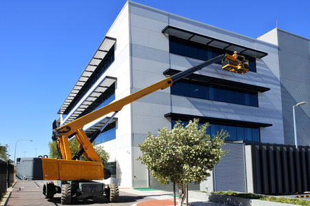 PERTH, WA - MAY 02 2021:Worker using an articulated boom lift beside a building exterior.Articulated...