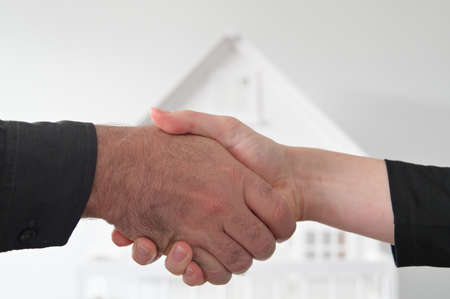 Two people (male and female) are shaking hands against a white house. Mortgage, housing market, home loans and property, management concept. No people. Copy spaceの写真素材